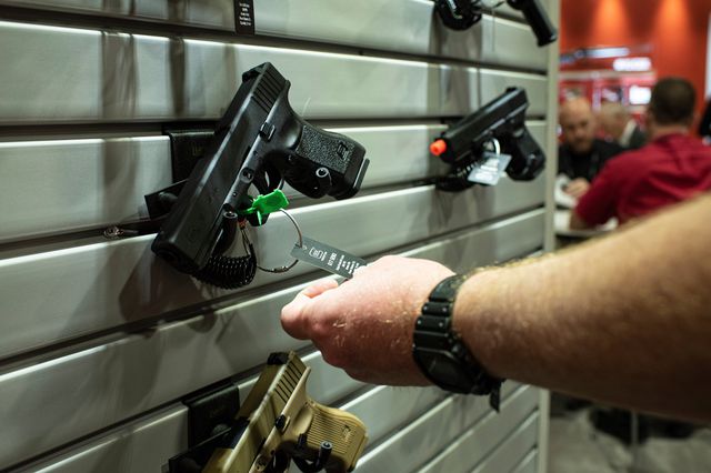 A man at a gun show in Las Vegas in 2020 inspects the tag of a handgun.
